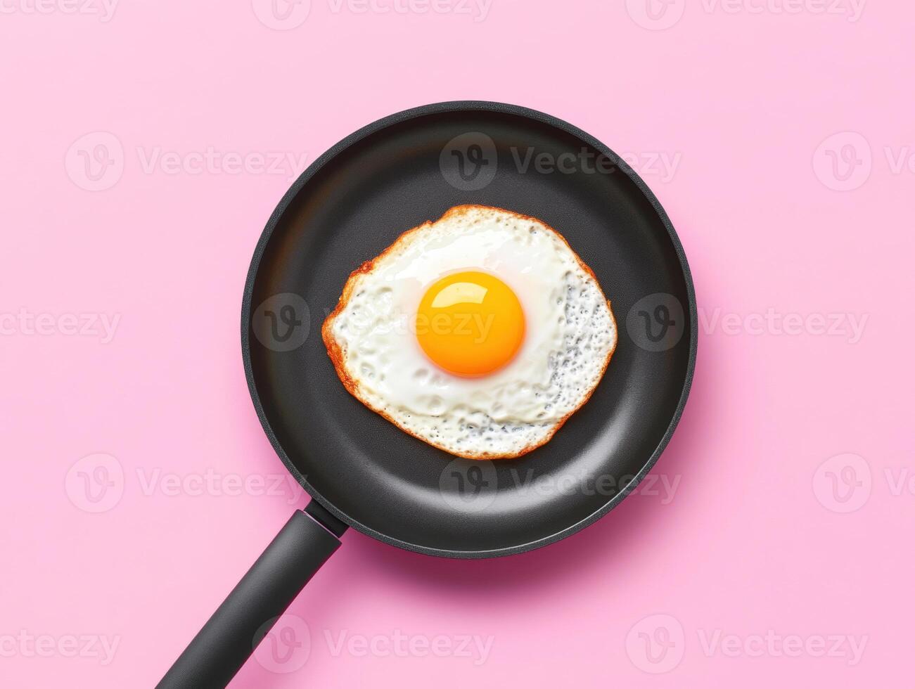 Fried egg in a pan on a pink background ready for breakfast photo