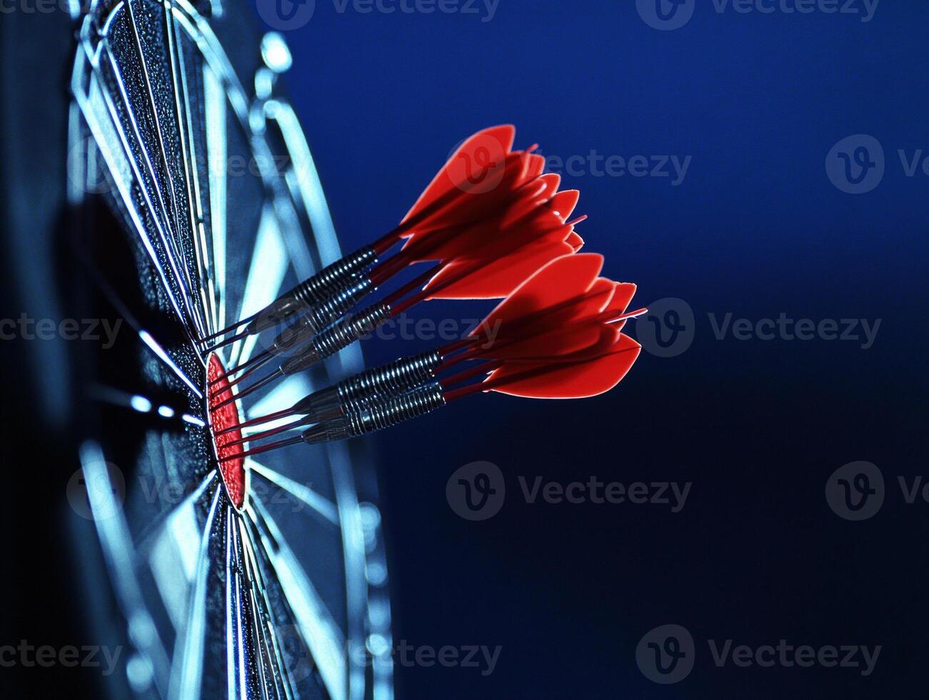 Darts hitting the bullseye on a dark blue dartboard photo