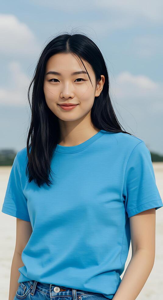 A woman in a blue shirt and jeans standing on a beach photo