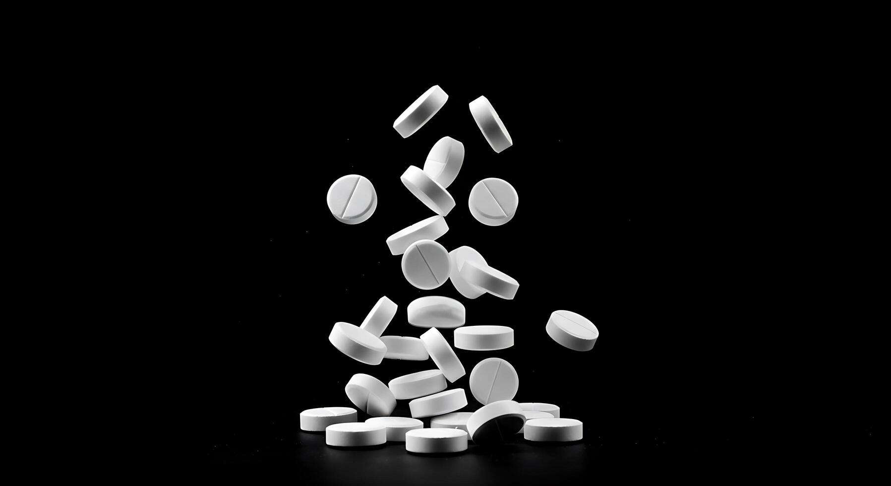 White pills falling on a black background photo