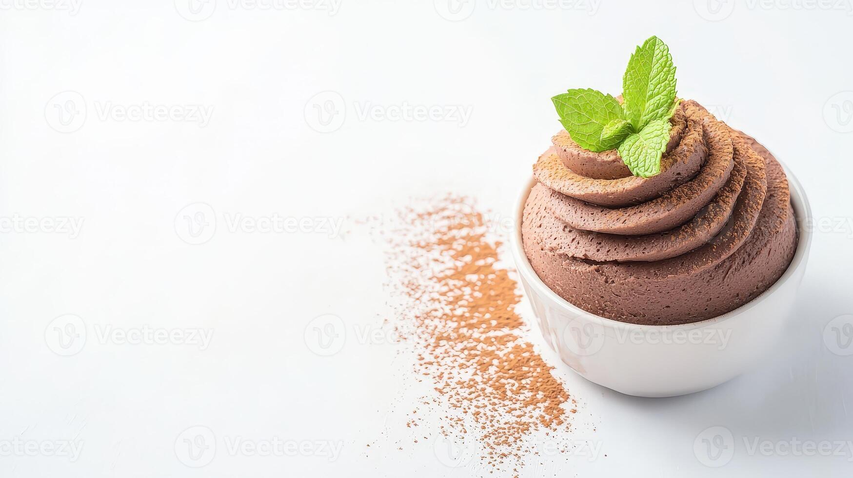A delectable chocolate mousse dessert sits in a small white bowl garnished with fresh mint leaves and cocoa powder on a bright white background perfect for culinary or food blogs. photo