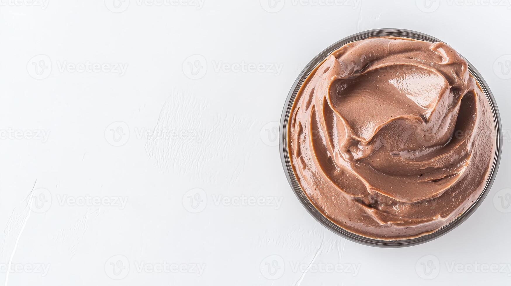 A rich and decadent chocolate cream dessert filling sits in a clear glass bowl on a white background perfect for culinary websites or dessert recipes. photo