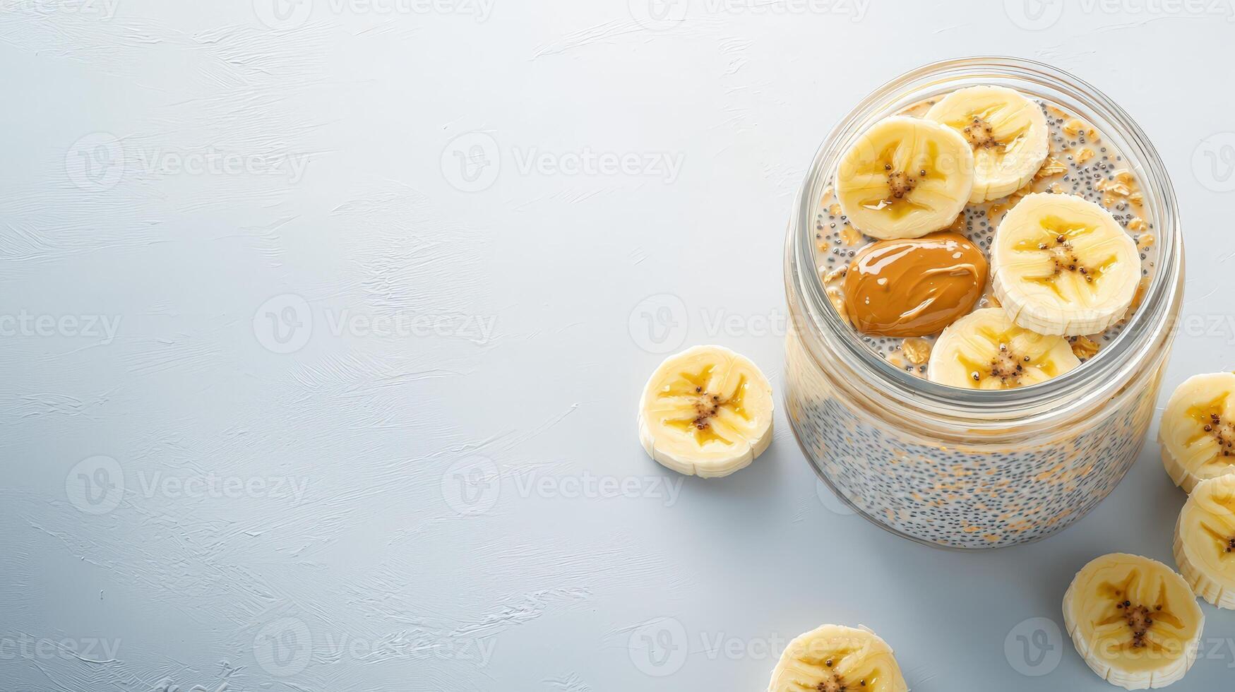 Delicious and healthy chia seed pudding with banana slices and peanut butter in a glass jar on a light blue background perfect for a nutritious breakfast or snack. photo
