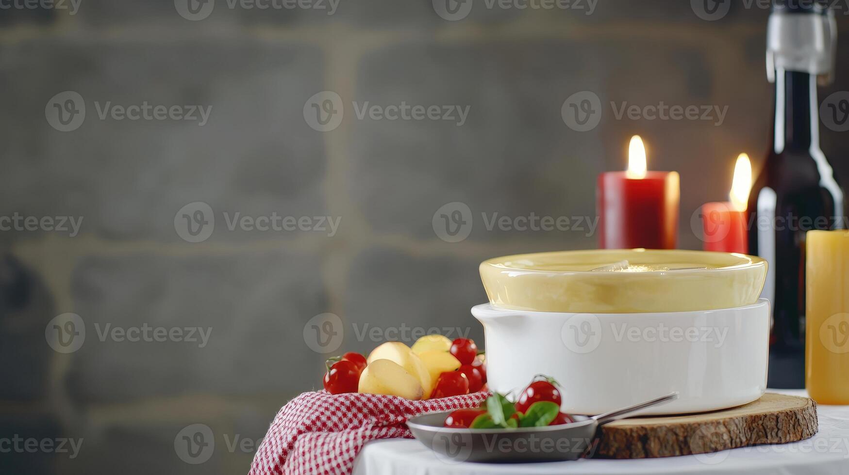 A rustic still life featu a double boiler of creamy cheese fondue next to fresh cherries and potatoes on a wooden board with lit candles and a wine bottle creating a warm photo
