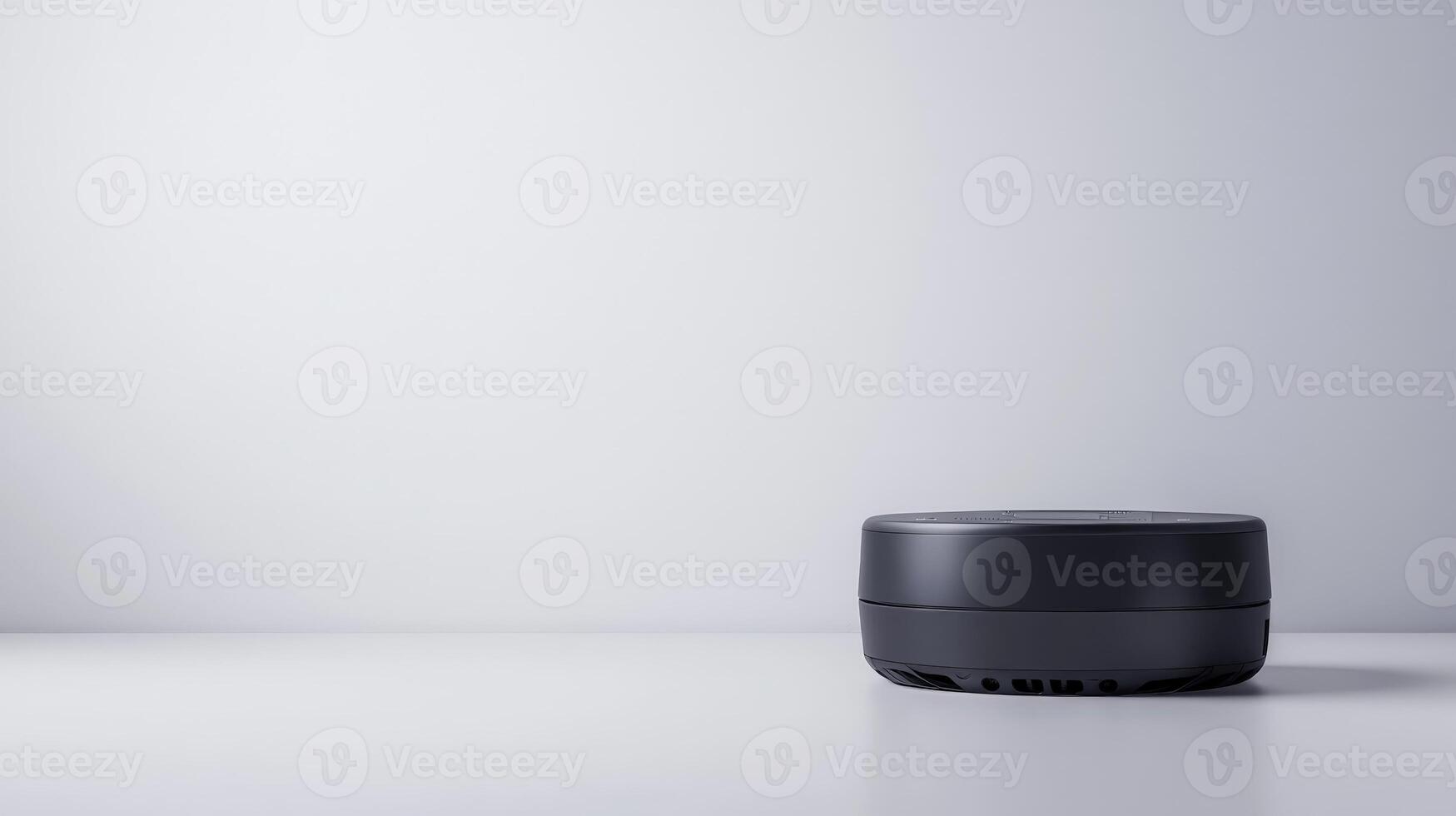 A black speaker sitting on a table in front of a white wall photo