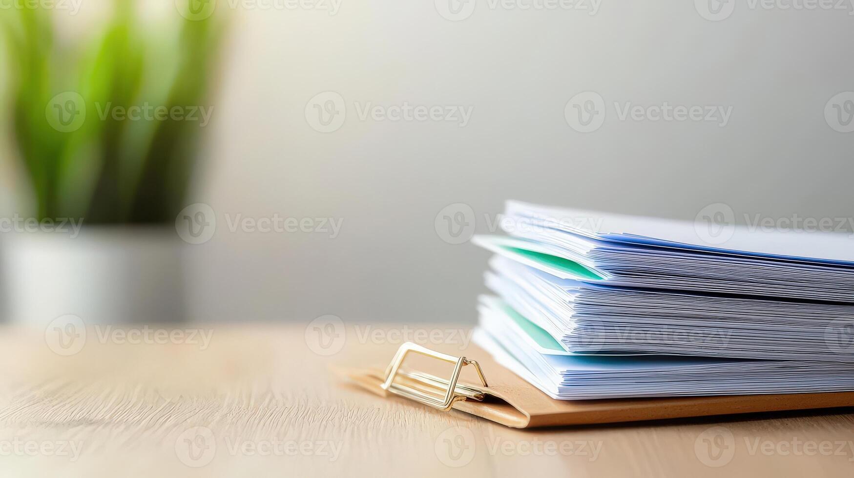 Stack of papers on wooden table with potted plant photo