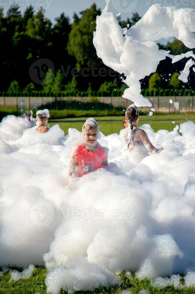 Children playing in outdoor foam party with bubbles on a sunny day. photo