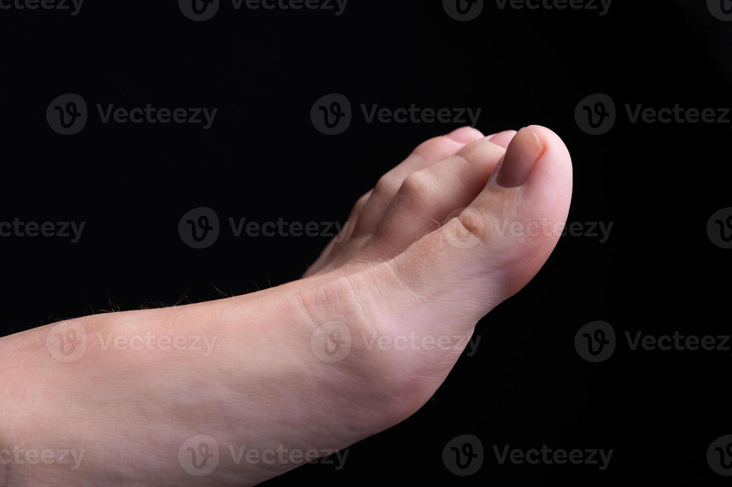 Barefoot feet, on black background. Close-up shot of healthy beautiful female feet. Health and beauty concept. Top view of human foot with neutral manicure or pedicure photo