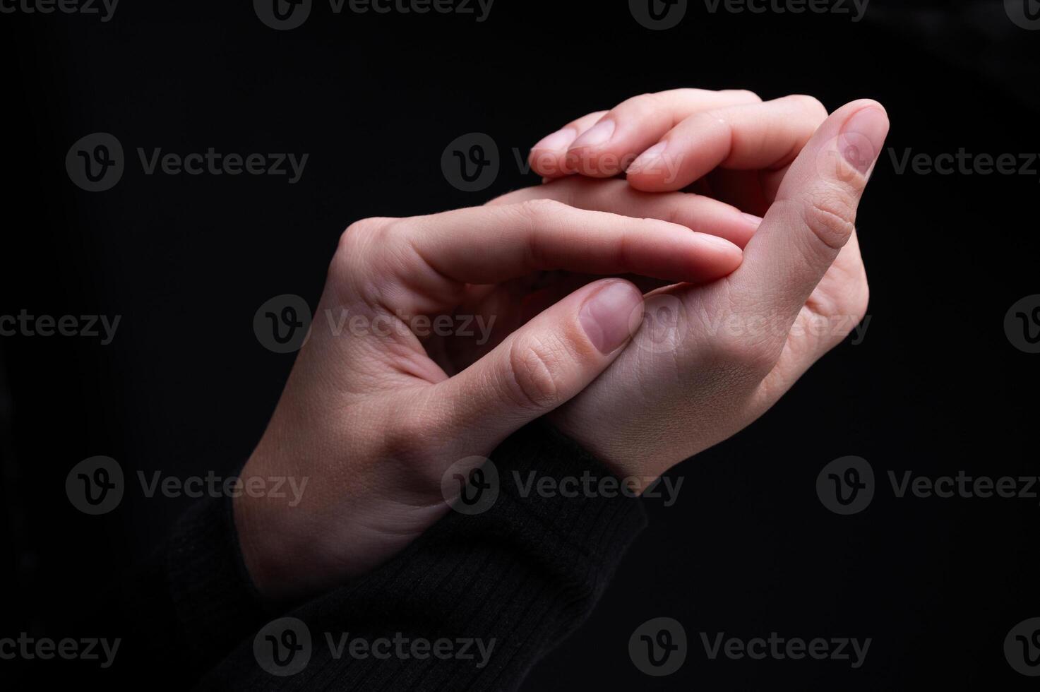 Close-up image of beautiful female hands with delicate pink manicure on nails on black background. Hand skin care, manicure and beauty treatments. Elegant and graceful hands with thin graceful fingers photo