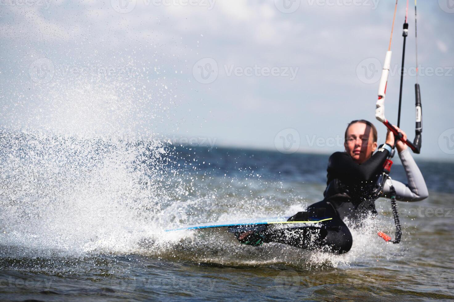 A view through a telephoto lens of a kitesurfer doing a trick with a darkslide. Focus on the splashes. The athlete is out of focus photo