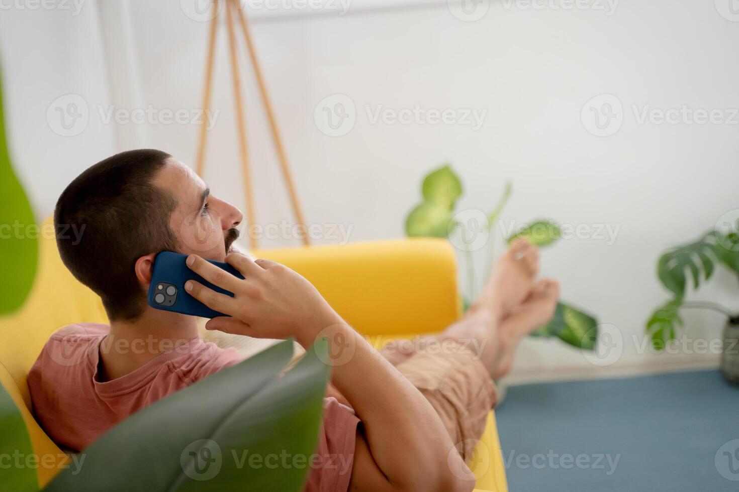 Relaxed man is casually talking on the phone while seated in his cozy living room space photo