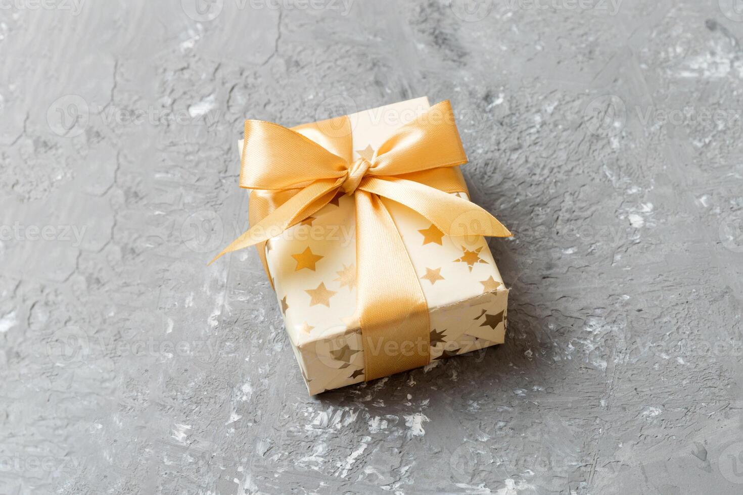wrapped Christmas other holiday handmade present in white paper with gold ribbon on colored background. Present box, decoration of gift on colored table, top view with copy space photo