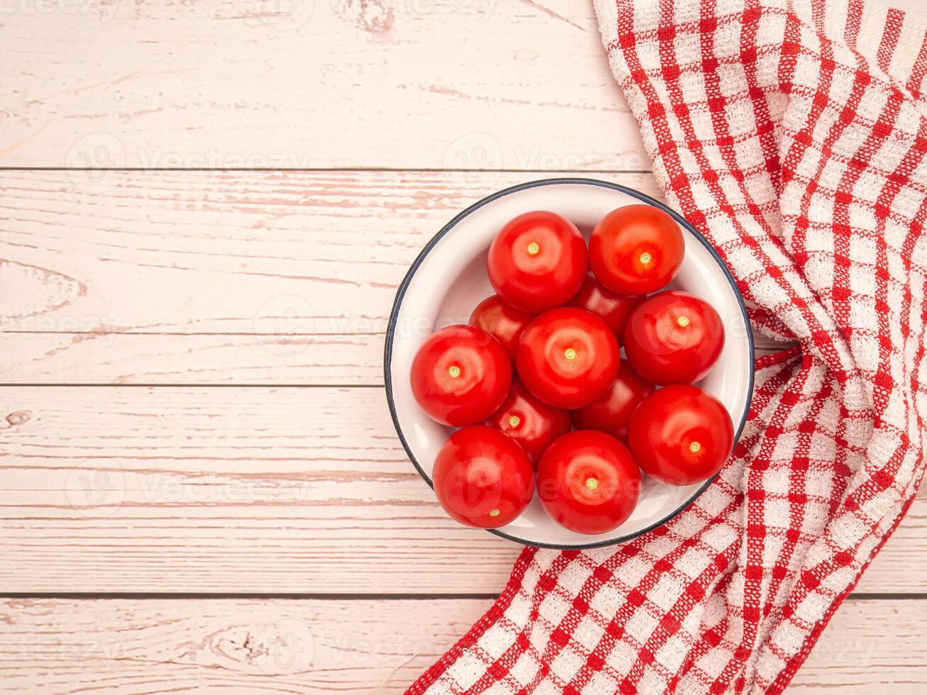 Top view of resh tomatoes on a white plate with a cloth on a wooden table. photo