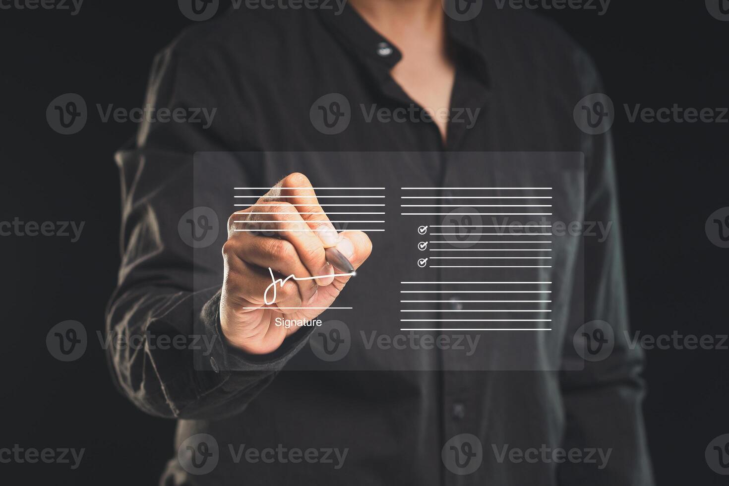Close-up of a businessman uses a pen to sign electronic documents on a virtual screen while standing on a black background. photo