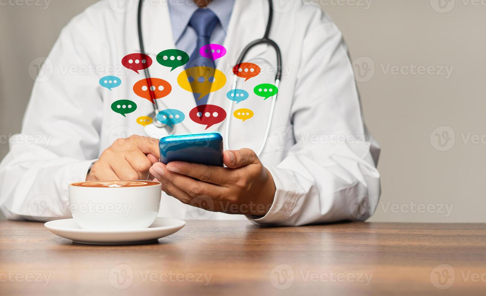 Doctor in a uniform using a smartphone with colorful chat icons on application digital web and social media while sitting at the table photo