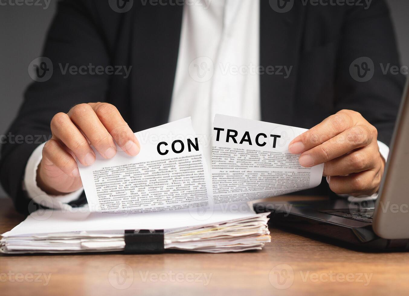 Businessman in a suit tearing up a contract while sitting at the table. photo