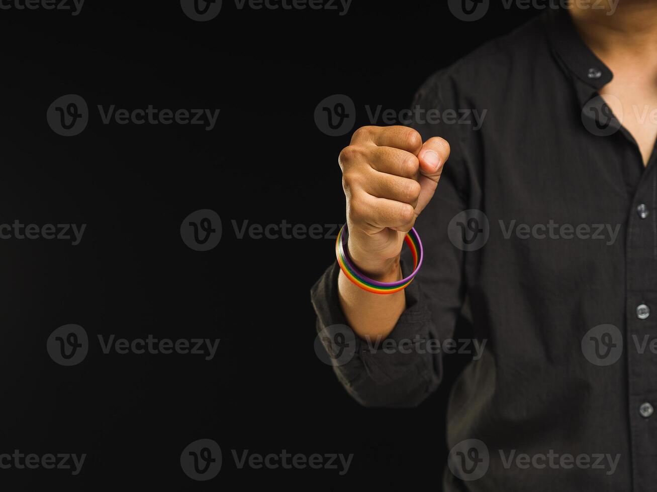 Hand fist with rainbow wristbands in a hand while standing against a black background photo