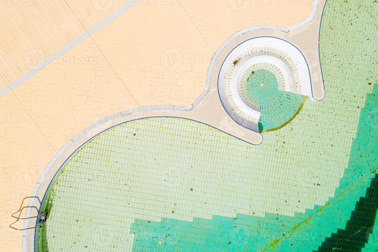 dirty green water and tile pattern in a neglected pool, aerial zenithal view photo