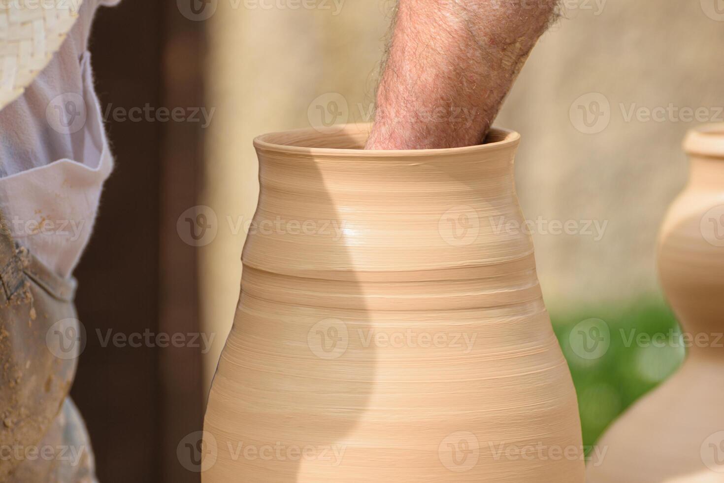 close view of an artisan's arm working with clay on a pottery wheel photo