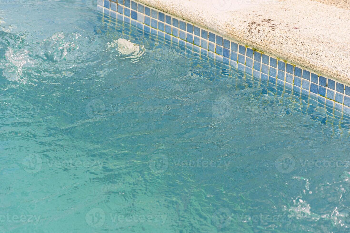 refreshing blue pool water with splashing detail, swimming pool corner with mosaic tiles and splashing water photo