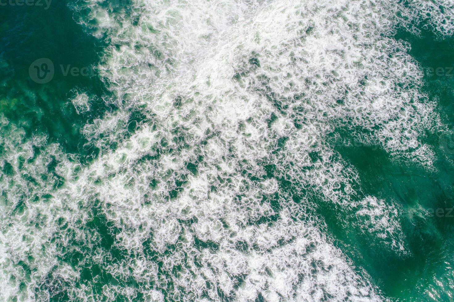 aerial perspective of foam of a dynamic breaking wave, top down view drone photography photo