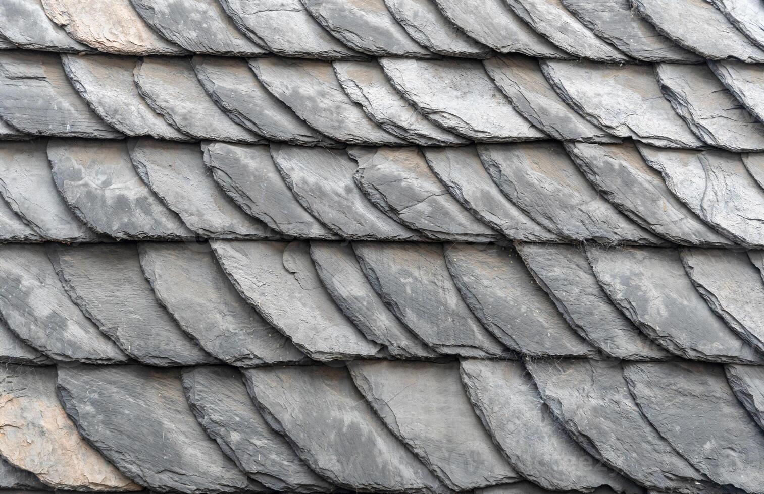 Traditional slate roof tiles are overlapping, creating a textured and patterned surface, providing durable and weather resistant protection for the building photo