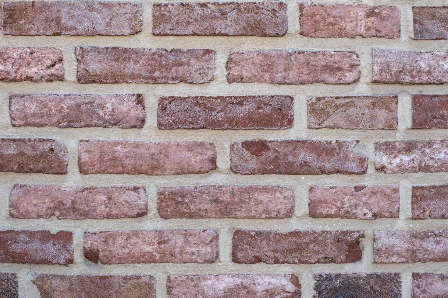 Even rows of red variegated bricks create a classic pattern of stretcher brickwork, an architectural detail for any design project, photo