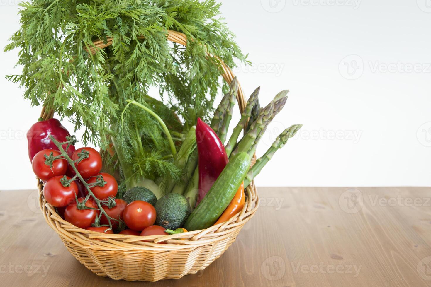 fresh assorted Vegetables in a basket on a wooden table, consumer vegetarian basket, tomatoes, fennel, paprika, asparagus,cucumbers, avocado, Healthy eating concept, top view photo