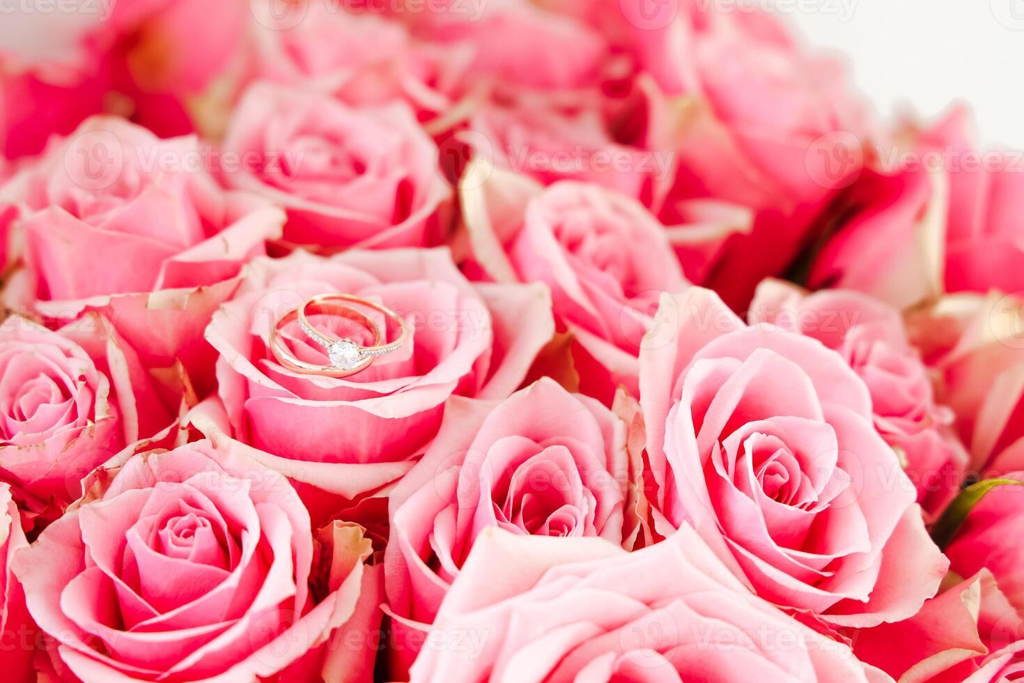 Close-up view of wedding rings nestled in a bouquet of pink roses at a romantic celebration photo