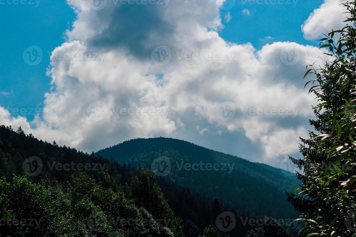Clouds gather above mountains during midday in a serene natural landscape photo