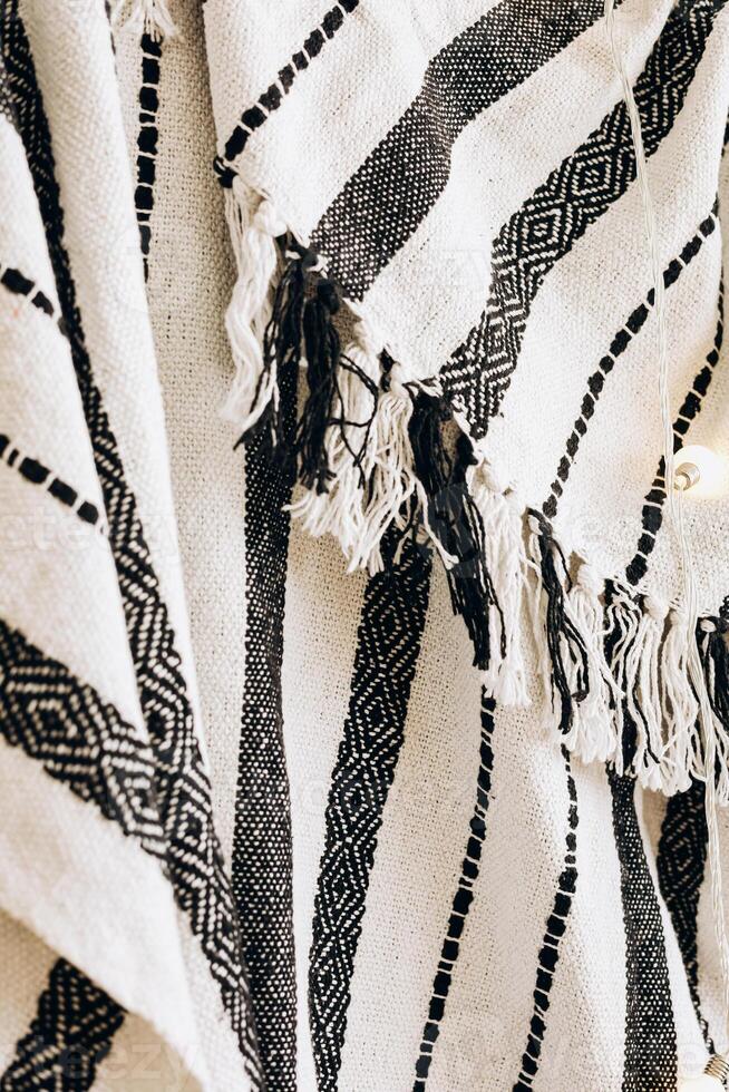 Handwoven textile featuring geometric patterns and fringed edges displayed in a cozy setting photo