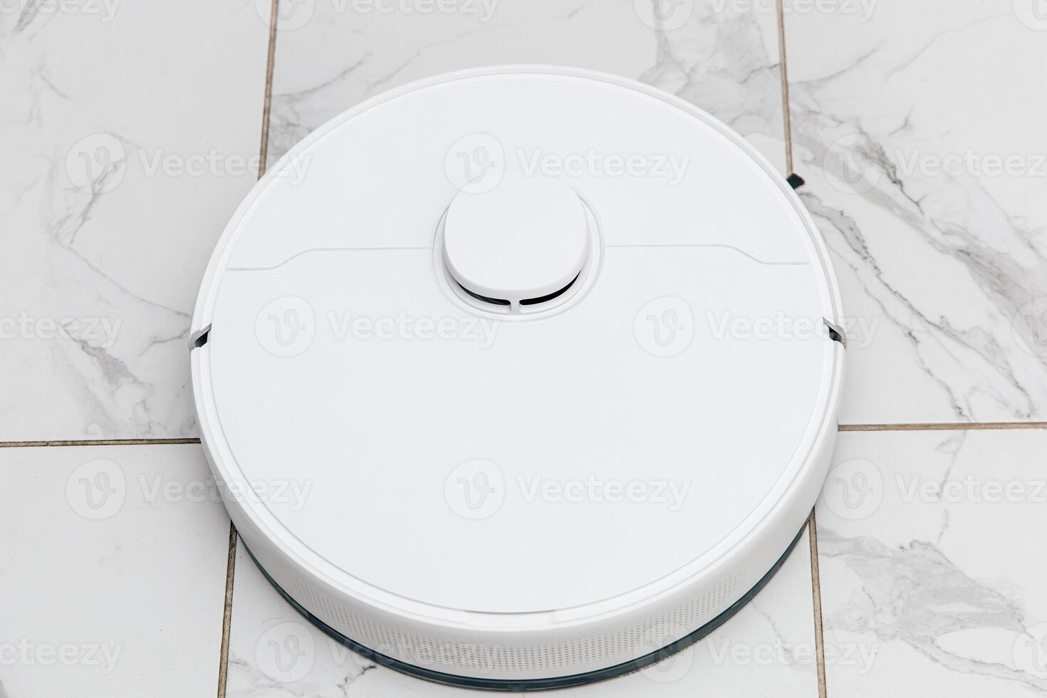 Robotic vacuum cleaner working on polished floor tiles in a bright living room photo