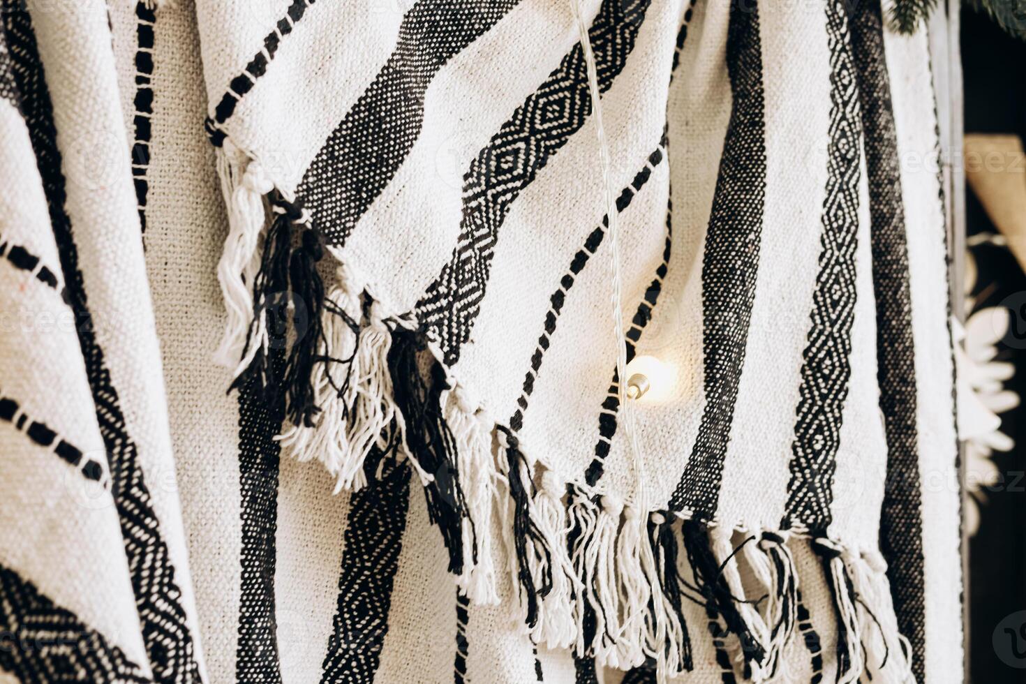 Handwoven textile with black and white patterns hanging in a craft store during daytime photo