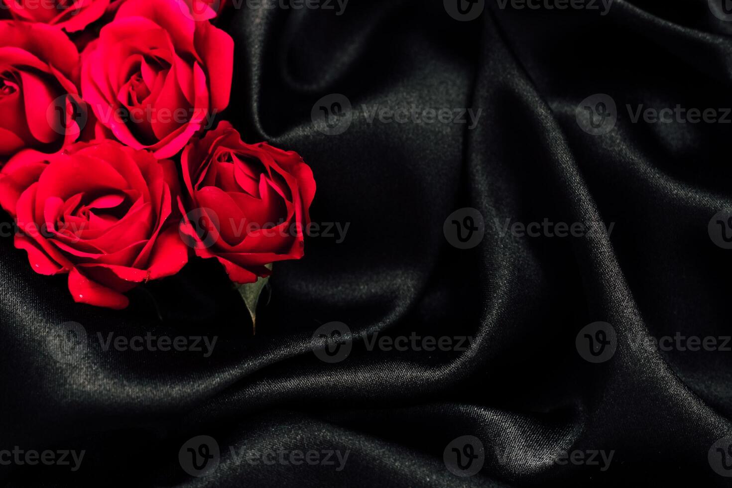 Red roses arranged on elegant black fabric create a striking and romantic display photo