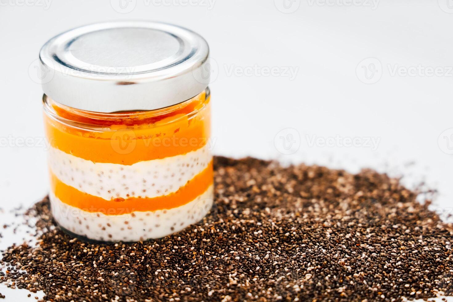 Chia pudding layered with fruit puree served with chia seeds on a white background photo