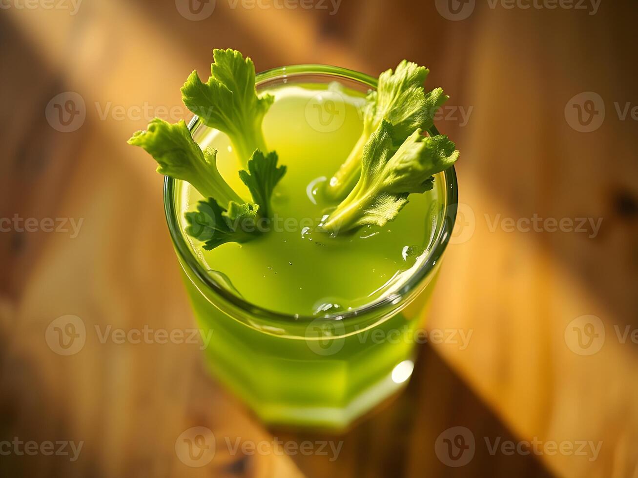 A glass of fresh celery juice with celery garnish on a wooden table photo