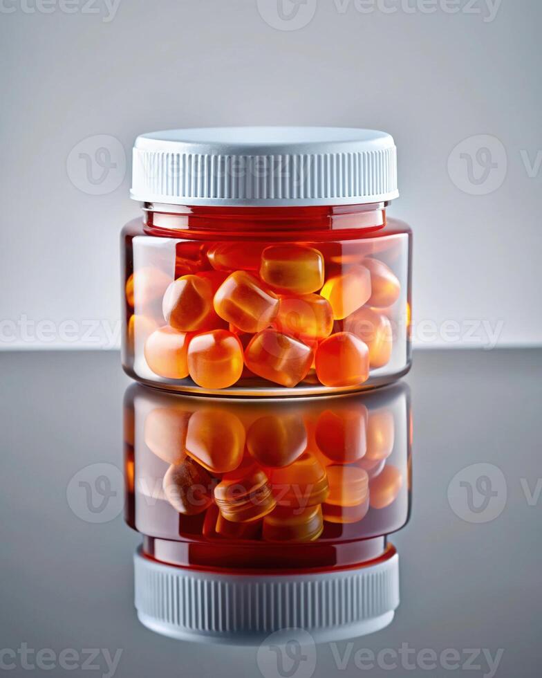 A jar filled with orange pills on a reflective surface photo