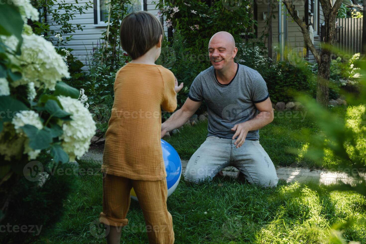 Father and small child having fun with inflatable ball on lawn, enjoying summer together. photo