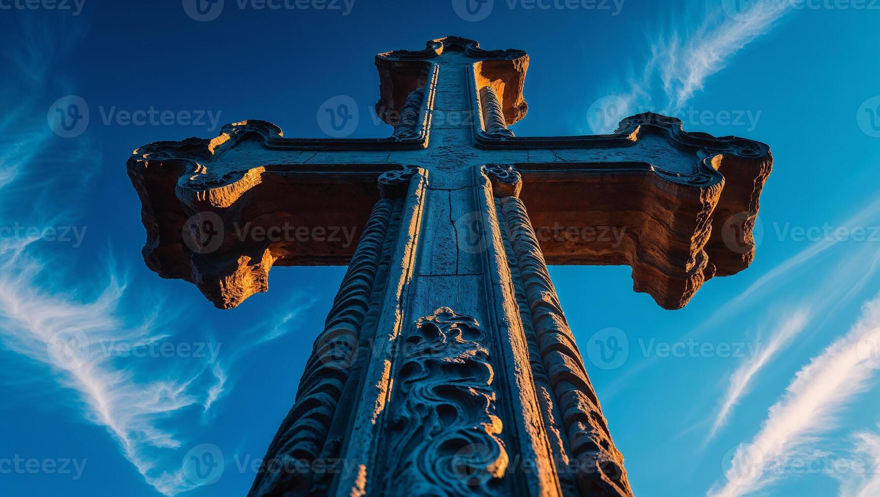 Large stone cross standing tall against blue sky photo