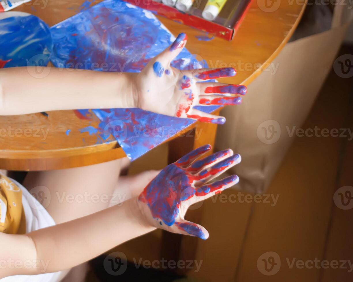Close-up of child hands smearing bright paints. Kids artistic creativity. photo