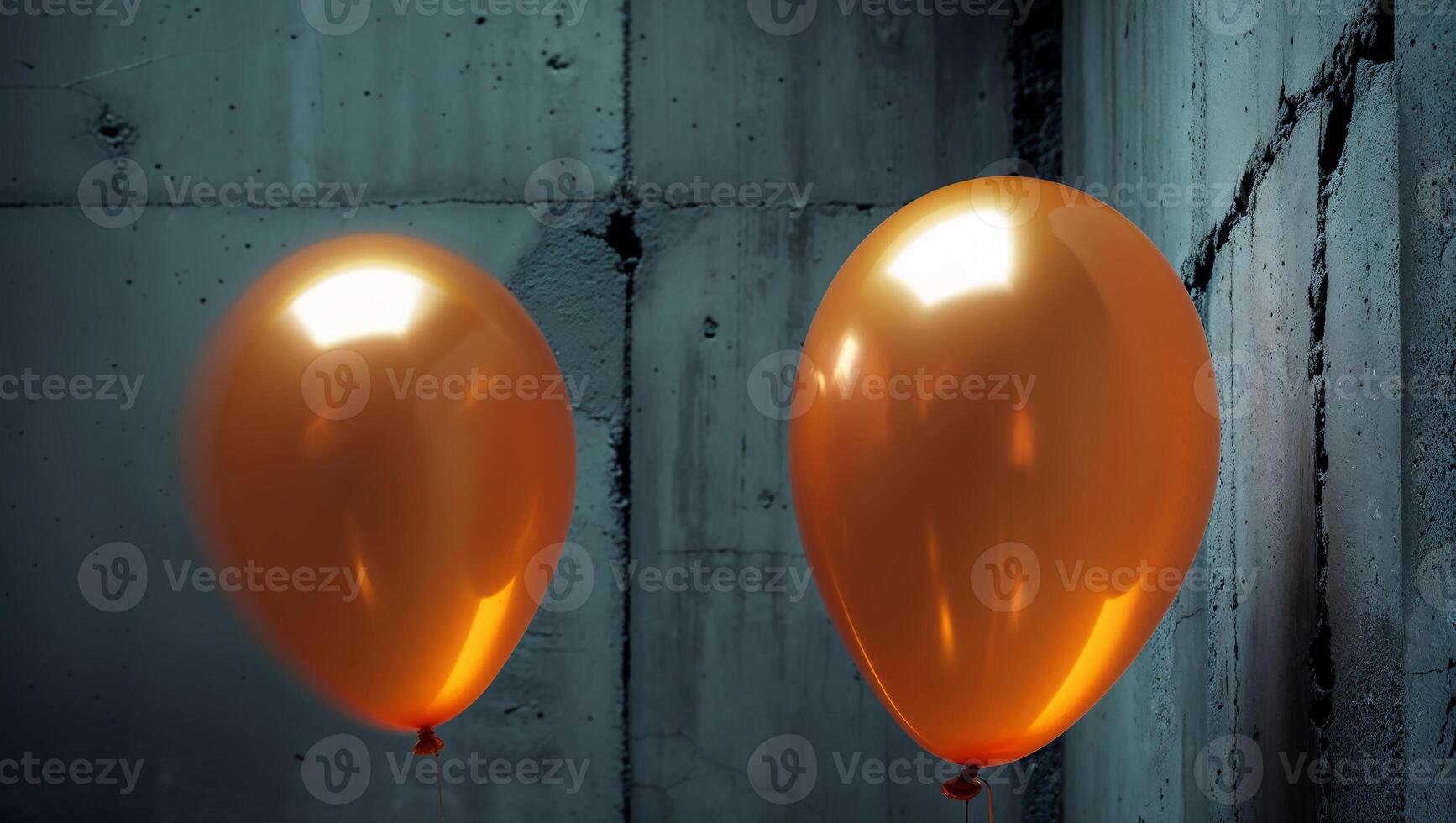 Two orange balloons floating against a concrete wall photo