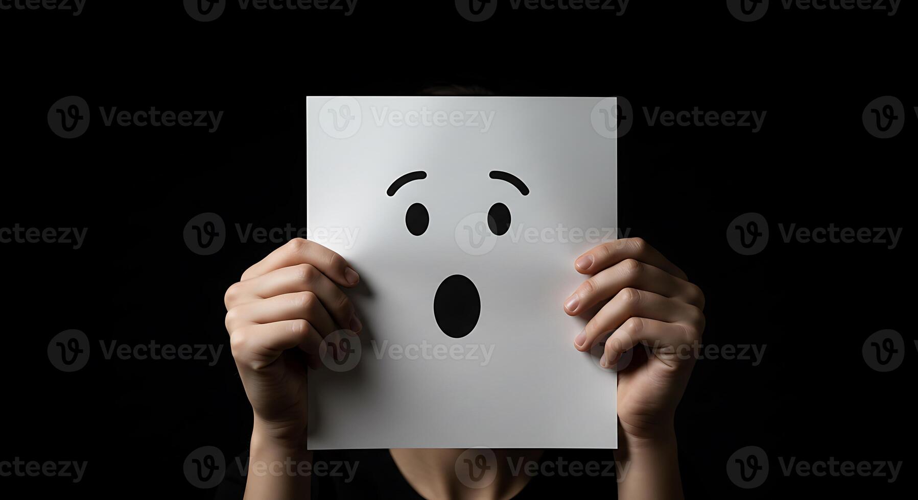 A person holding up a paper with a face on it photo