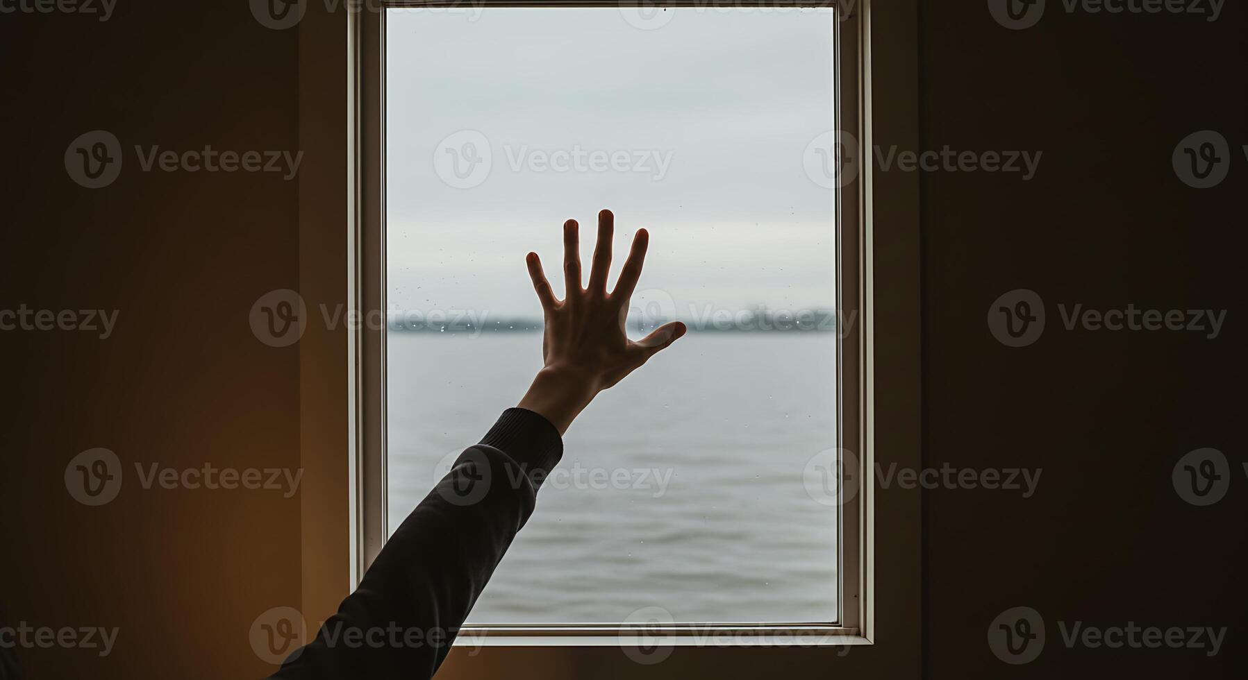 A person reaching out to a window with a view of the water photo