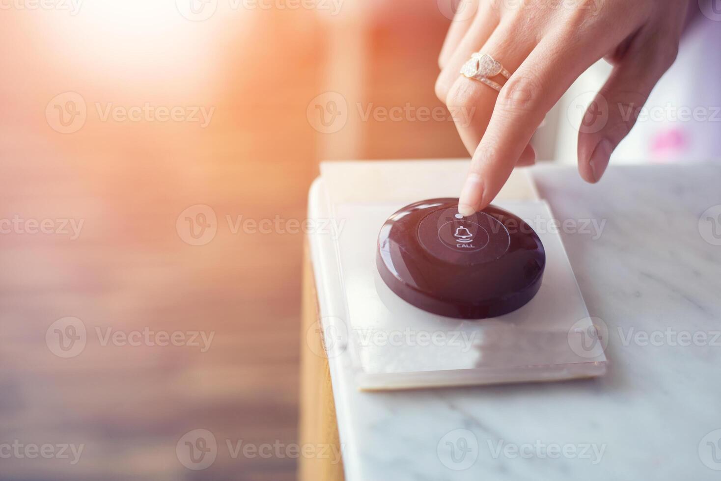 Hand pressing the call button on table photo