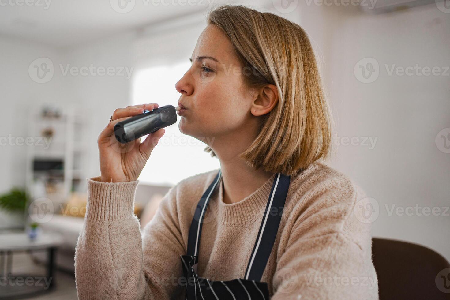 Woman enjoying a moment of relaxation while vaping indoors photo