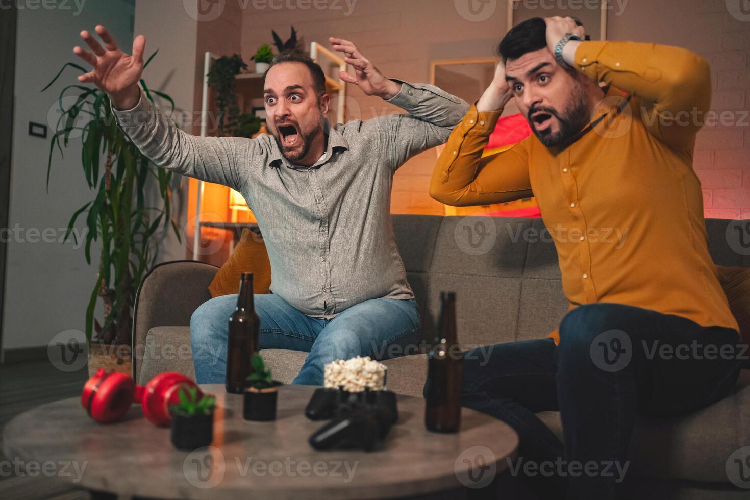 Friends share an intense moment as they react to a surprising plot twist while enjoying a gaming night at home photo