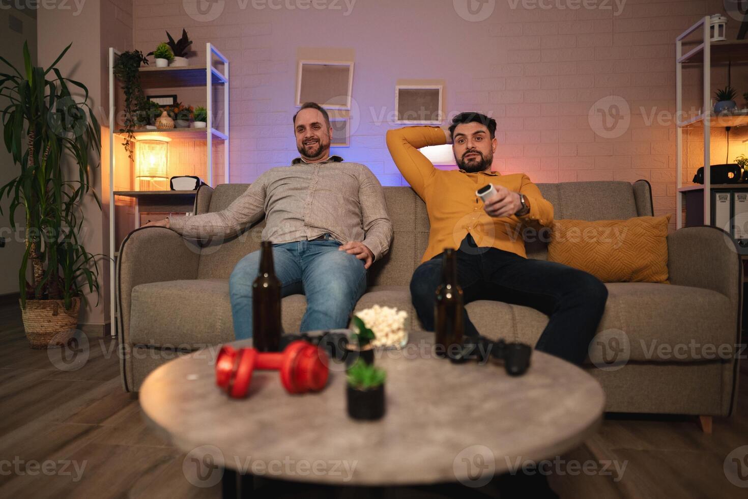 Friends relax on a cozy couch, enjoying a gaming night filled with laughter and snacks in a modern living room photo