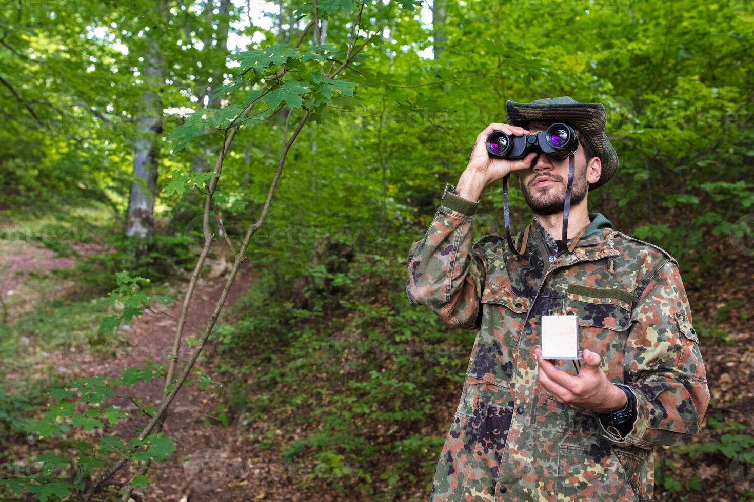 Soldier exploring forest using binoculars and gps device photo