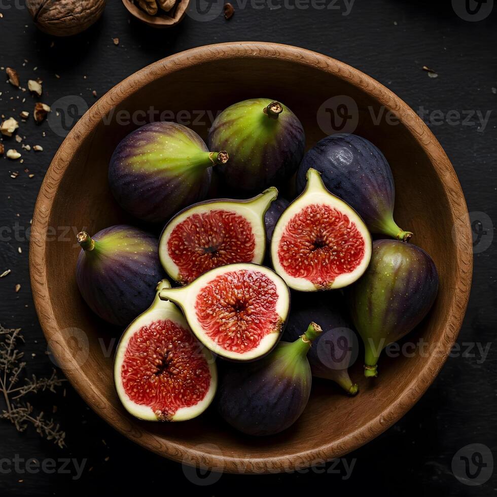A top-down view shows a wooden bowl filled with whole and halved figs along with nuts on a dark surface photo