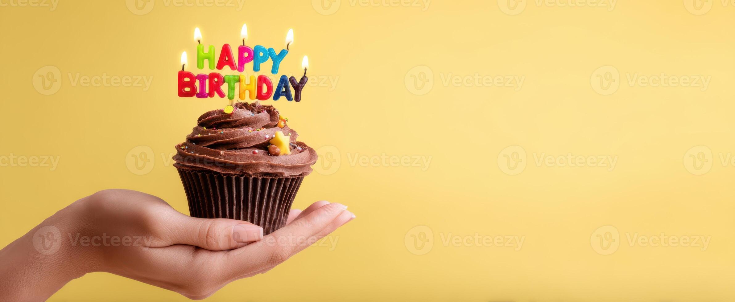 The delightful chocolate cupcake with a cheerful birthday greeting and candles. photo